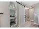 Bright bathroom featuring neutral walls with storage nooks, a white sliding barn door, and a tan tile floor at 9481 Highland Oak Drive # 602, Tampa, FL 33647