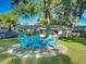 A circle of blue Adirondack chairs on a concrete patio surrounded by green grass and mature trees at 9616 Oak Ridge Ave, Riverview, FL 33578