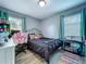 Cozy bedroom with a black metal bed frame, wood floors, and plenty of natural light at 9616 Oak Ridge Ave, Riverview, FL 33578