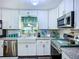 Well-lit kitchen showcasing stainless steel appliances, white cabinets, and a farmhouse style sink at 9616 Oak Ridge Ave, Riverview, FL 33578