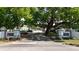 View of the community entrance with lush green trees and well-maintained grounds at 100 Glennes Ln # 207, Dunedin, FL 34698