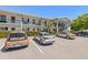 Exterior shot of a bright two-story condo building with a covered entrance and well-manicured shrubs at 100 Glennes Ln # 207, Dunedin, FL 34698