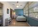 Inviting sunroom with a twin bed, wooden floors, bright turquoise accent wall, and lots of natural light at 100 Glennes Ln # 207, Dunedin, FL 34698