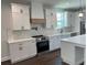 Modern kitchen with white cabinets, stainless steel appliances, quartz countertops, and a wood accent hood at 107 E Park St, Tarpon Springs, FL 34689