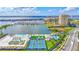 Stunning aerial view of waterfront property with a marina, swimming pools, and tennis courts against a blue sky at 130 Riviera Dunes Way # 203, Palmetto, FL 34221