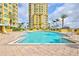 Resort-style pool area surrounded by lush landscaping and towering condominiums on a sunny day at 130 Riviera Dunes Way # 203, Palmetto, FL 34221