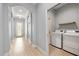 Hallway view of modern laundry room with new front load washer and dryer units and convenient shelving at 1423 W Wood St, Tampa, FL 33604