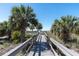 Scenic boardwalk framed by lush palms, leading to a beautiful beachfront at 200 120Th W Ave # 3A, Treasure Island, FL 33706