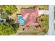 Overhead view of property featuring a screened pool, red roof, landscaped yard, and circular driveway at 2017 Godfrey Ave, Spring Hill, FL 34609
