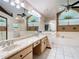 Bright bathroom featuring double sinks, marble countertop, and a large window with a fan at 2017 Godfrey Ave, Spring Hill, FL 34609