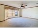 Well-lit living room with neutral carpeting, a ceiling fan, and a large window with vertical blinds at 2017 Godfrey Ave, Spring Hill, FL 34609