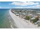 Picturesque aerial view of the coastline with sandy beach, ocean waves, and a charming town nestled beside the shore at 321 Bahia Vista Dr, Indian Rocks Beach, FL 33785