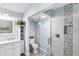 Bright bathroom with a single vanity, a large, glass-enclosed shower with decorative pebble tile, and marble walls at 321 Bahia Vista Dr, Indian Rocks Beach, FL 33785