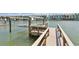 Dock featuring boat lift, water access, and views of the colorful waterfront townhomes on the canal at 321 Bahia Vista Dr, Indian Rocks Beach, FL 33785