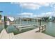 Dock featuring boat lift, water access, and views of the colorful waterfront townhomes on a partly sunny day at 321 Bahia Vista Dr, Indian Rocks Beach, FL 33785