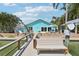 Bright waterfront home featuring a private dock with seating and vibrant turquoise exterior paint at 321 Bahia Vista Dr, Indian Rocks Beach, FL 33785