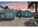 Charming turquoise home with well-manicured front yard, palm tree, and a two car garage on a beautiful day at 321 Bahia Vista Dr, Indian Rocks Beach, FL 33785