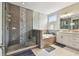 Bright bathroom featuring a glass-enclosed shower with decorative tile, a soaking tub, and double sink vanity at 4007 W Gray St, Tampa, FL 33609