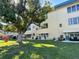 Exterior view of the condo building showcases large shade tree and lush green lawn at 5750 80Th N St # B203, St Petersburg, FL 33709