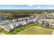 Aerial view of a neighborhood with a lake, playground, and wooded preserve in the background at 7334 Ashcroft Dr, Wesley Chapel, FL 33545