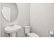 A clean, neutral-toned powder room with a pedestal sink and toilet, maximizing space at 7334 Ashcroft Dr, Wesley Chapel, FL 33545