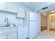Kitchen featuring white cabinets, stainless steel sink, and tiled flooring leading to another room at 10190 Imperial Point W Dr # 8, Largo, FL 33774