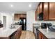 This kitchen has granite countertops, wood-look tile floors, and stainless steel appliances including a black refrigerator at 10196 Cross Timber Ter, Land O Lakes, FL 34638