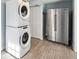 Functional laundry room with stacked washer/dryer, stainless steel fridge, and white louvered closet doors at 1225 26Th N St, St Petersburg, FL 33713