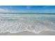 Beautiful beach view with clear turquoise water and gentle waves lapping onto the sandy shore at 1390 Gulf Blvd # 104, Clearwater, FL 33767
