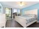 Sunlit bedroom with a balcony, dark wood floors, white furniture, and a glimpse of city views at 1390 Gulf Blvd # 104, Clearwater, FL 33767