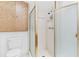 Compact bathroom featuring a shower with glass doors, white tile, and wood-finished cabinet above the toilet at 147 Bluff View Dr # 206, Belleair Bluffs, FL 33770