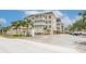 Beautiful condo building exterior with palm trees, lush landscaping, and ample parking at 147 Bluff View Dr # 206, Belleair Bluffs, FL 33770