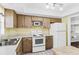 Traditional kitchen with white appliances, wood cabinets, and a stainless-steel sink, offers a functional space for cooking at 147 Bluff View Dr # 206, Belleair Bluffs, FL 33770