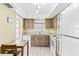 A bright kitchen with tiled floors, wooden cabinets, white appliances, and a small dining area near the window at 147 Bluff View Dr # 206, Belleair Bluffs, FL 33770