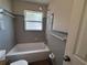 Bathroom featuring a tub and shower combination with blue and gray tiles plus a window at 212 S Church Ave # 105, Tampa, FL 33609