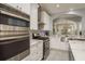 Contemporary kitchen with stainless steel appliances, white cabinetry, mosaic backsplash, and archway to living area at 264 Seagate Ct, Dunedin, FL 34698