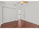 Bright bedroom features hardwood floors, a ceiling fan, and a closet with white bi-fold doors at 426 Village Dr, Tarpon Springs, FL 34689