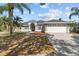 Charming single-story home featuring a manicured lawn, mature trees, and a two-car garage at 426 Village Dr, Tarpon Springs, FL 34689