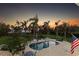 Backyard view with a large pool, lush landscaping, and an American flag at 450 Bayshore Dr, Terra Ceia, FL 34250