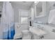 Updated bathroom features a shower with blue accents, a pedestal sink, and a window at 505 27Th N Ave, St Petersburg, FL 33704