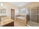 Bright bathroom features a double sink vanity, soaking tub, and separate shower with glass door at 627 Washita Stone Dr, Ruskin, FL 33570