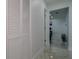 Hallway with marble floors, white walls, louvered closet doors, and an open doorway looking into another room at 6414 Larmon St, Tampa, FL 33634