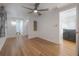 Open bedroom with sleek ceiling fan, light wood floors, and a glimpse into an adjacent bathroom and living space at 7006 N Duncan Ave, Tampa, FL 33604