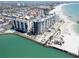 Aerial view of beachfront condos with pool, beach access, and beautiful turquoise waters at 7100 Sunset Way # 303, St Pete Beach, FL 33706