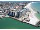 Aerial view of beachfront condos with pool, beach access, and beautiful turquoise waters at 7100 Sunset Way # 303, St Pete Beach, FL 33706