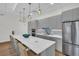 Modern kitchen features sleek gray cabinets, stainless steel appliances, an island with seating, and pendant lighting at 7100 Sunset Way # 303, St Pete Beach, FL 33706
