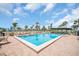 Community swimming pool surrounded by lounge chairs, palm trees, and clear skies on a sunny day at 7100 Sunset Way # 303, St Pete Beach, FL 33706