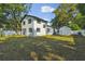 Spacious backyard featuring lush green lawn, mature trees, and a newly painted white exterior with black trim at 7210 8Th N Ave, St Petersburg, FL 33710