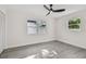Bright bedroom featuring two windows, light gray floors, a ceiling fan, and closet with bifold doors at 7210 8Th N Ave, St Petersburg, FL 33710
