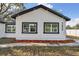 Front exterior view of the white home with a matching garage and contrasting black trim at 7210 8Th N Ave, St Petersburg, FL 33710